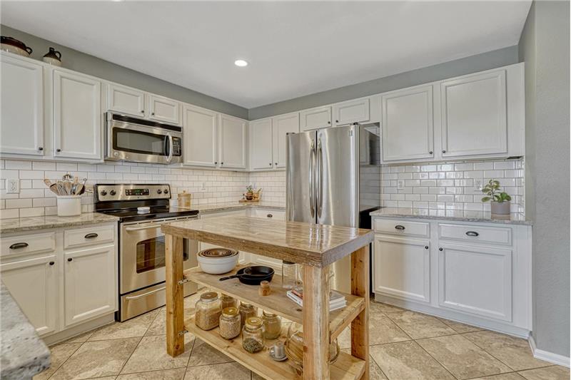 The stylish Kitchen offers white cabinets, granite countertops, subway tile backsplash, pantry, & water filtration system.