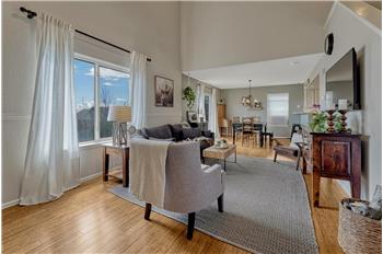 The Living Room boasts tall ceilings, beautiful bamboo flooring, and a large window with backyard views.