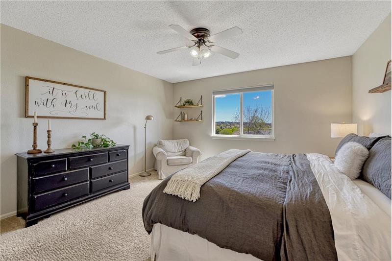 The spacious Primary Bedroom is a private retreat with lighted ceiling fan and sitting area.