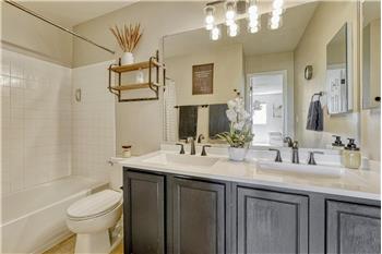 Primary Bathroom with updated dual sink vanity, mirror, and tiled tub/shower.