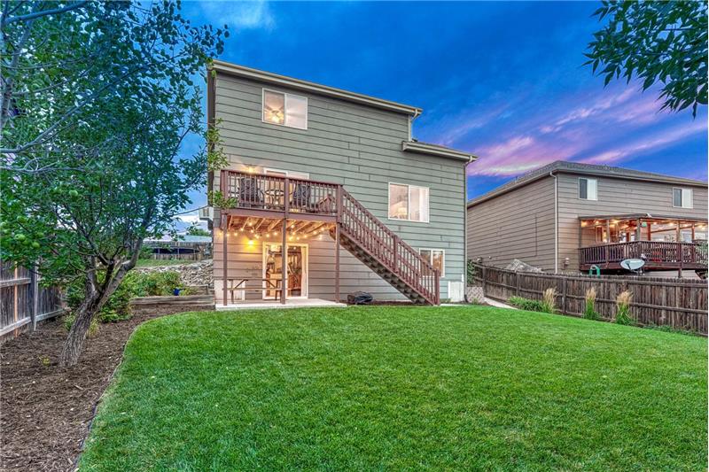 Beautifully landscaped backyard with auto sprinklers, raised planter beds, apple tree, and lilac bushes.
