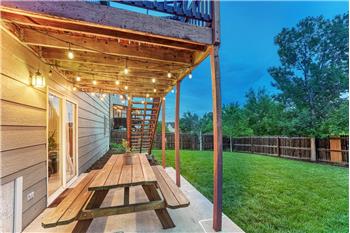 Sunset view of lighted covered patio and backyard.