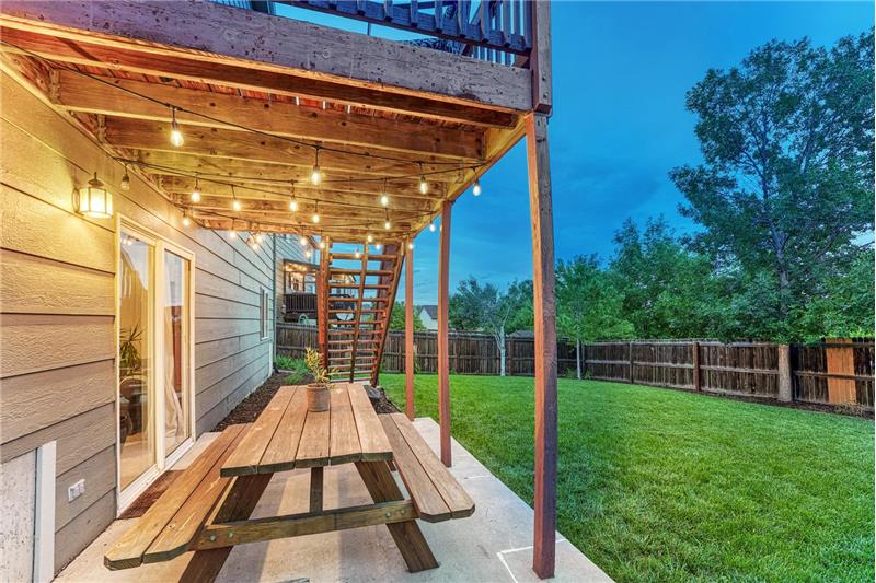 Sunset view of lighted covered patio and backyard.