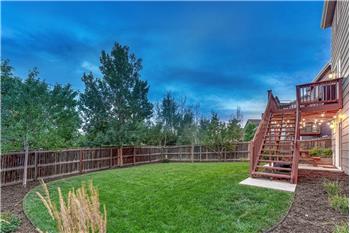 Sunset view of fenced backyard with mature trees surrounding the lot for privacy.