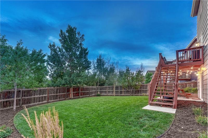 Sunset view of fenced backyard with mature trees surrounding the lot for privacy.