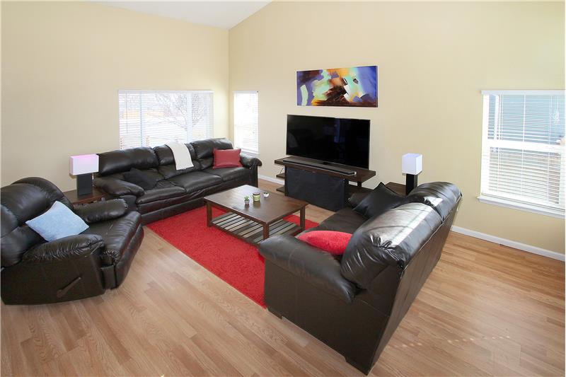 Bright and clean living room with wood laminate flooring that continues throughout the home