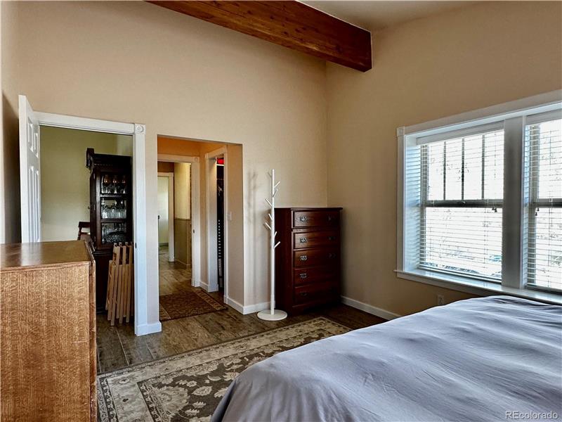 Reverse view of primary bedroom showing door to dining room and opening to walk-in closet and bathroom