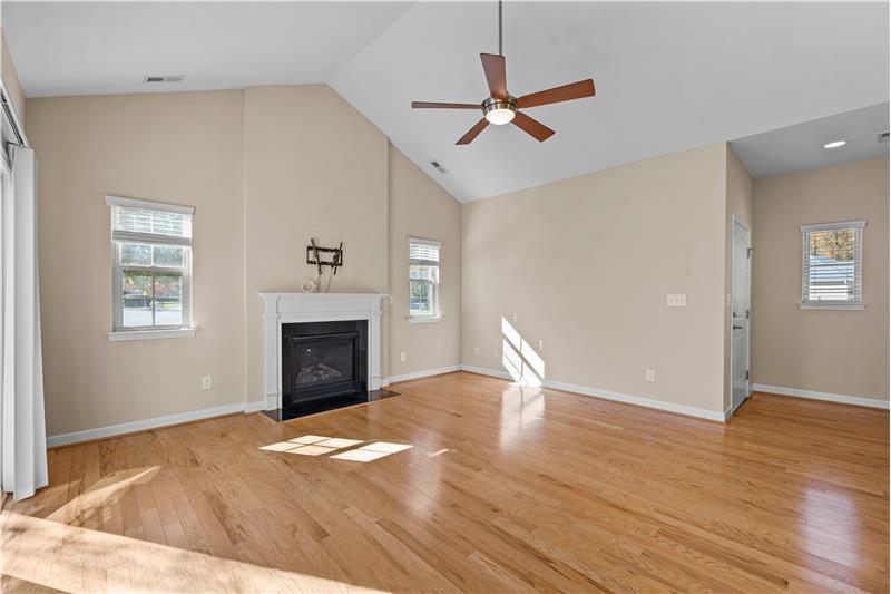 Great room features hardwood floors, vaulted ceiling, gas fireplace, upgraded ceiling fan with light