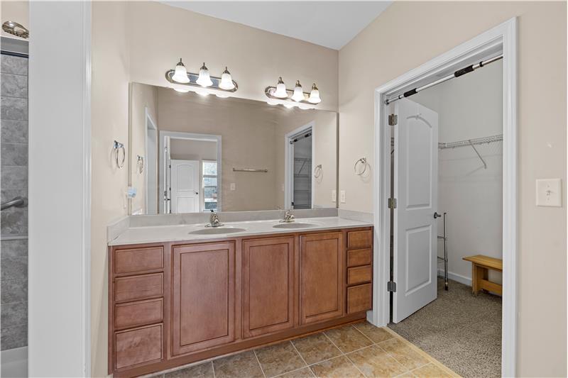 Primary bathroom features tile floors, cultured marble counters, en-suite walk-in closet