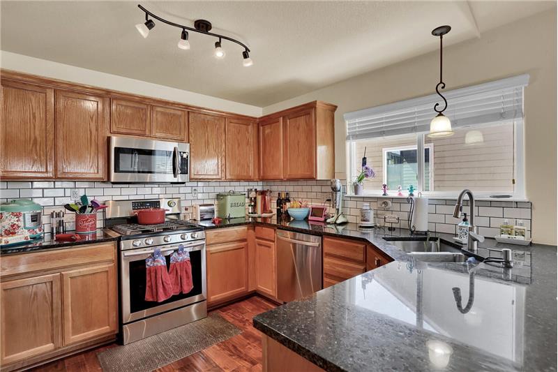 The Kitchen features a counter bar, cabinets with granite countertops, subway tile backsplash, & under-mount lights