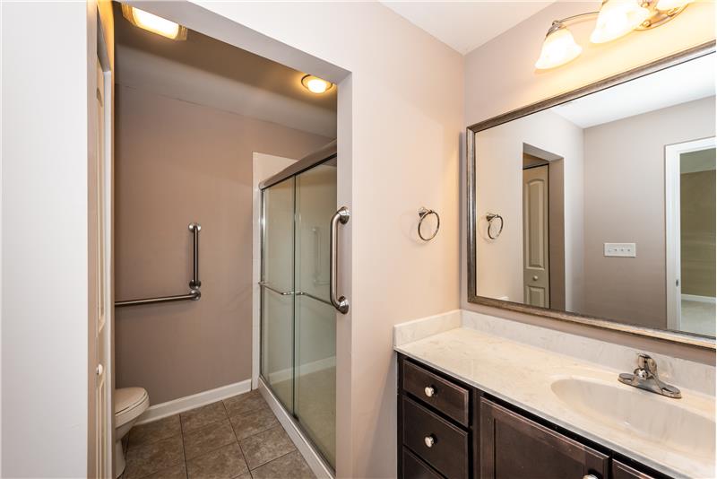 Owner's bathroom features features large, step-in shower, tile flooring, grab bars for safety.