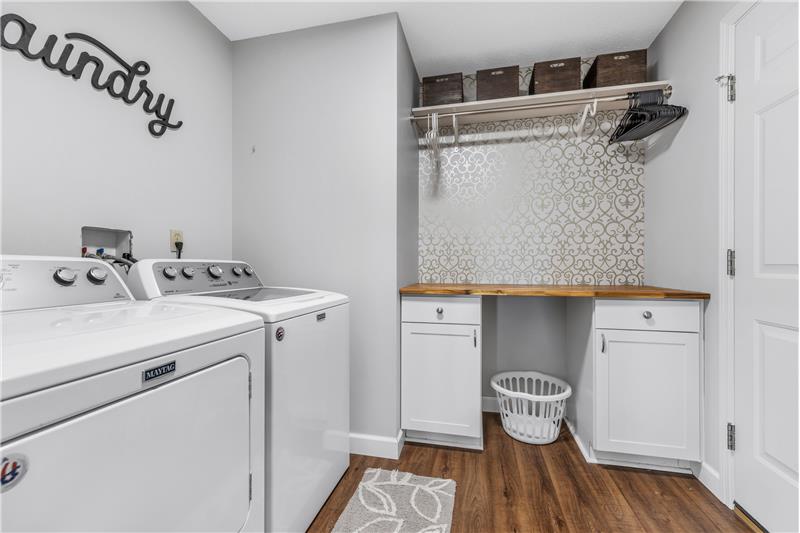 Main Floor Laundry with storage cabinets a folding counter and hanging rod