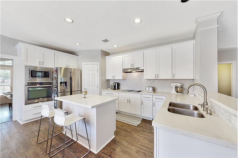 The spacious kitchen offers stainless steel appliances and an island along with quartz counters.