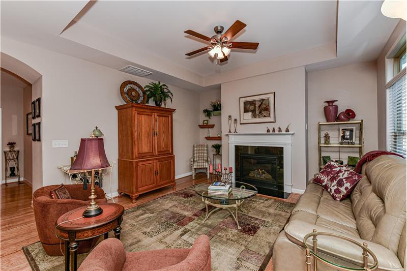 Spacious living room with gas log fireplace with decorative mantel. Trey ceiling adds an elegant architectural detail.