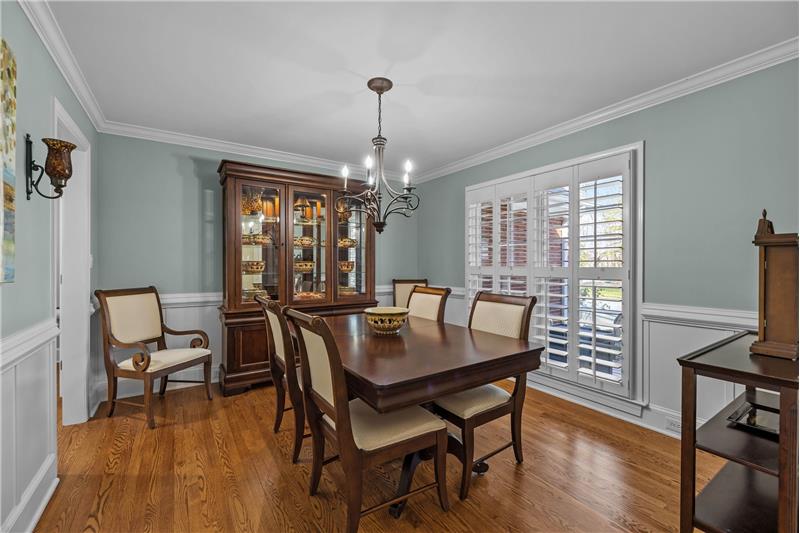 Dining room features hardwood floors, French-style windows, crown molding, wainscoting, custom plantation shutters.