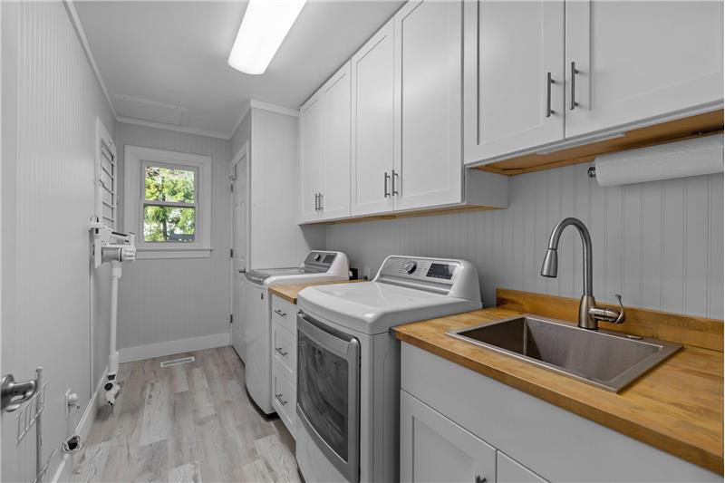 Fully remodeled laundry room with cabinets, utility sink, closet, built-in drying rack. Space for large washer and dryer.


