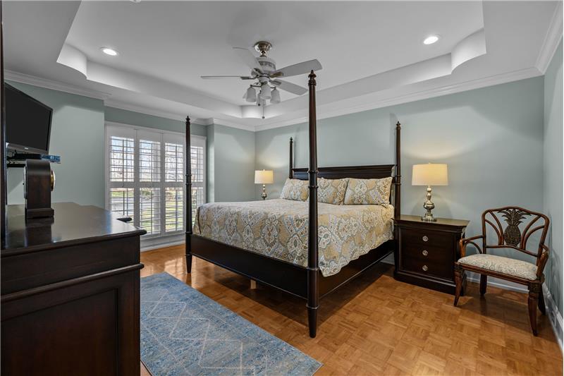 Serene and spacious primary bedroom with trey ceiling, recessed lights, French-style windows, custom, wood plantation shutters.
