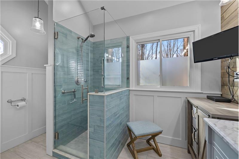 Fully remodeled, spa-inspired primary bathroom features custom, walk-in shower, frameless glass enclosure, designer tilework. 