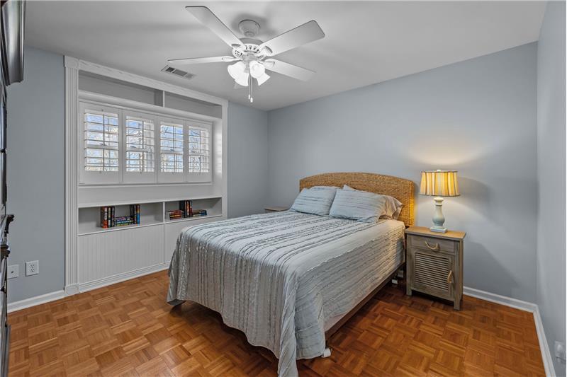 One of three bedrooms on home's second floor featuring parquet floors, ceiling fan with light, double closet, neutral decor.

