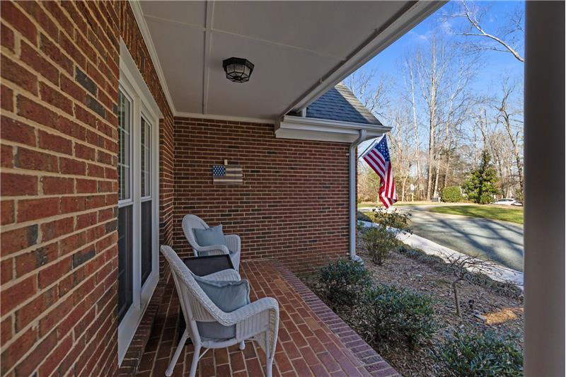 Inviting covered front porch with classic brick construction creates an ideal space to relax an welcome guests.