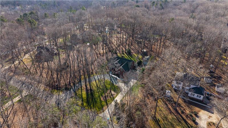 Aerial perspective showcases the home's private setting, surrounded by mature trees and established landscaping.