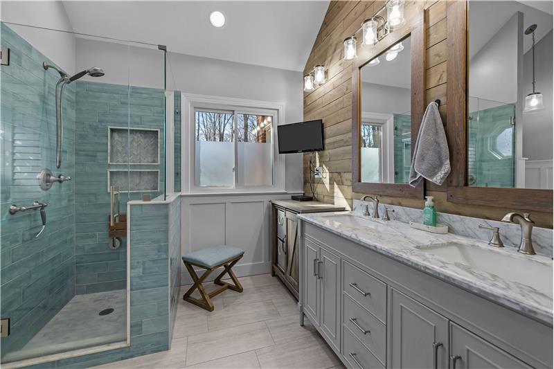 Double-sink vanity has abundant storage, stone countertops, modern hardware, complemented by wood-accent feature wall.
