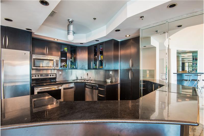 Open kitchen with black granite & stainless steel appliances.