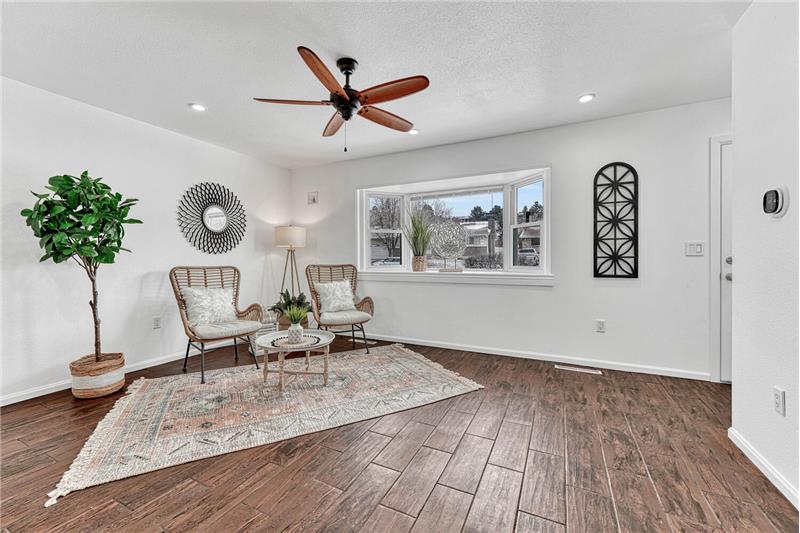 The Living Room features Wood Look Tile Floors, a Lighted Ceiling Fan, and Bay Window