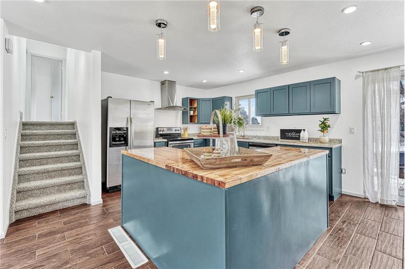 Island Kitchen with Pendant Lights and Stairs to the Upper Level