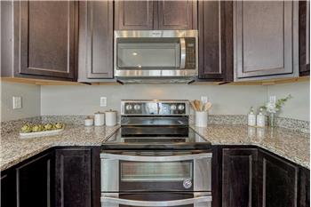 Stainless steel appliances include a smooth top range with double oven, microwave, dishwasher, and side by side refrigerator.