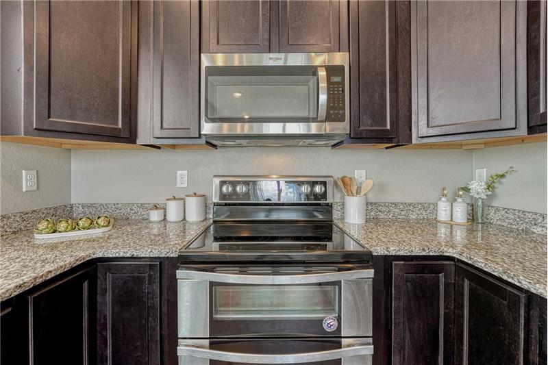 Stainless steel appliances include a smooth top range with double oven, microwave, dishwasher, and side by side refrigerator.