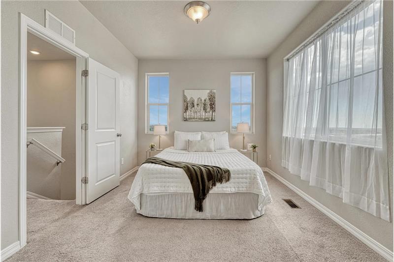 Upper level Primary Bedroom with wall of windows, neutral carpet, adjoining bathroom and walk in closet.