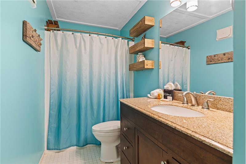 Our full bathroom boasts a large frameless mirror and tub.