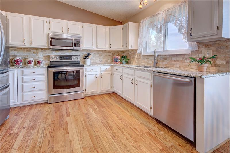 The Kitchen features cabinets with granite countertops and stone backsplash, and stainless-steel appliances