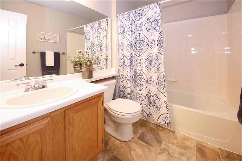 Main level Hall Bathroom with tile-look vinyl floor, a vanity, and tub/shower