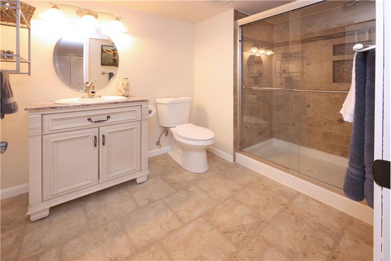 Updated Shower Bathroom with tile-look vinyl floor, vanity, mirror, and enclosed tiled shower