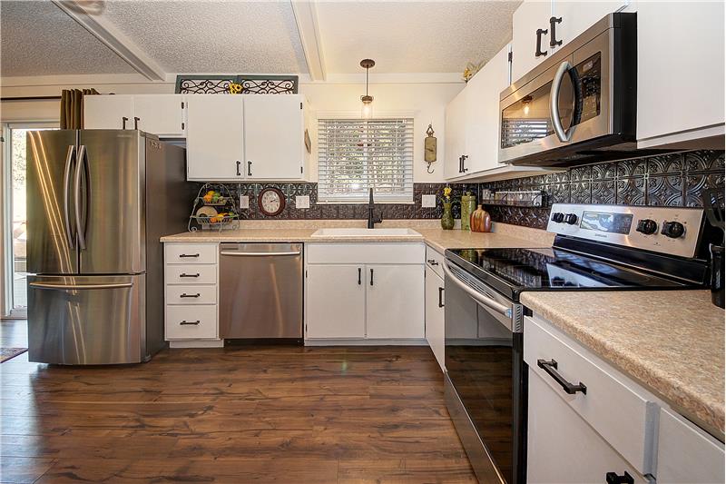 Kitchen with stainless steel appliances, backsplash, and wood laminate flooring