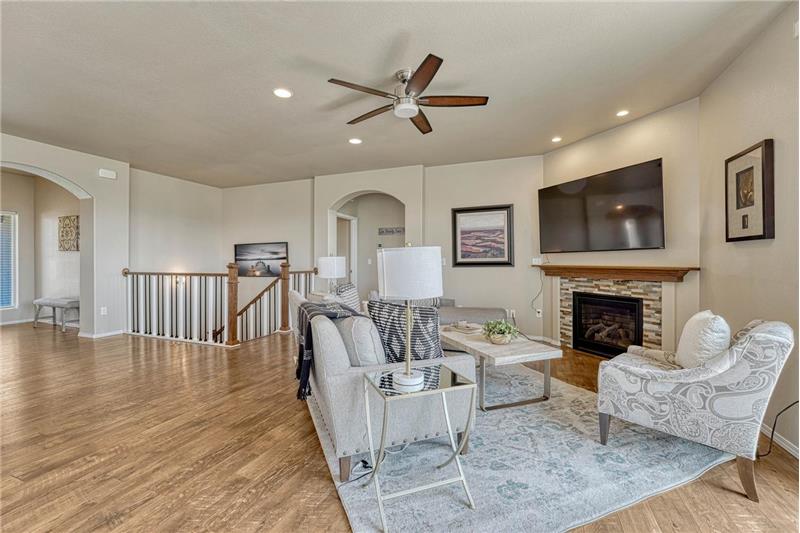 The Living Room features LVP flooring, a lighted ceiling fan, and gas fireplace with stone surround.
