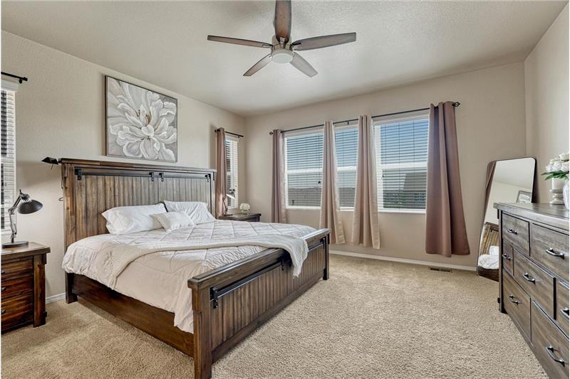 The main level Primary Bedroom is a private retreat with neutral carpet, a lighted ceiling, adjoining bathroom, & walk in closet