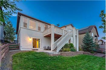 Fenced Backyard with auto sprinklers, partially covered patio, deck, and beautiful trees and shrubs.