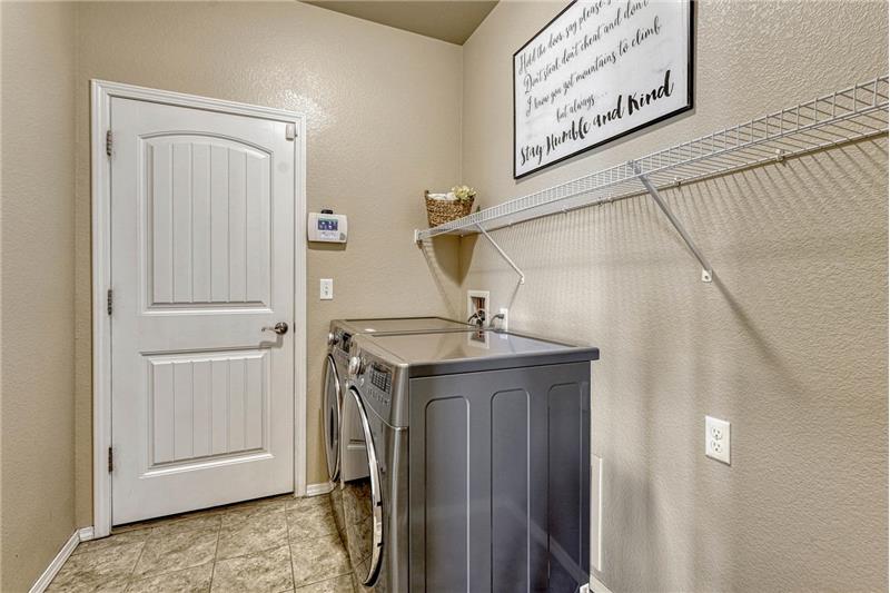 The Laundry Room has garage access and features tile flooring, a built in shelf and washer and dryer that stay.