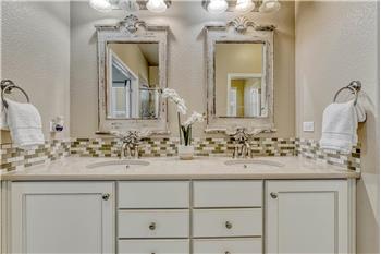 The Primary Bathroom features a beautiful dual sink quartz vanity with tiled backsplash and framed mirrors.