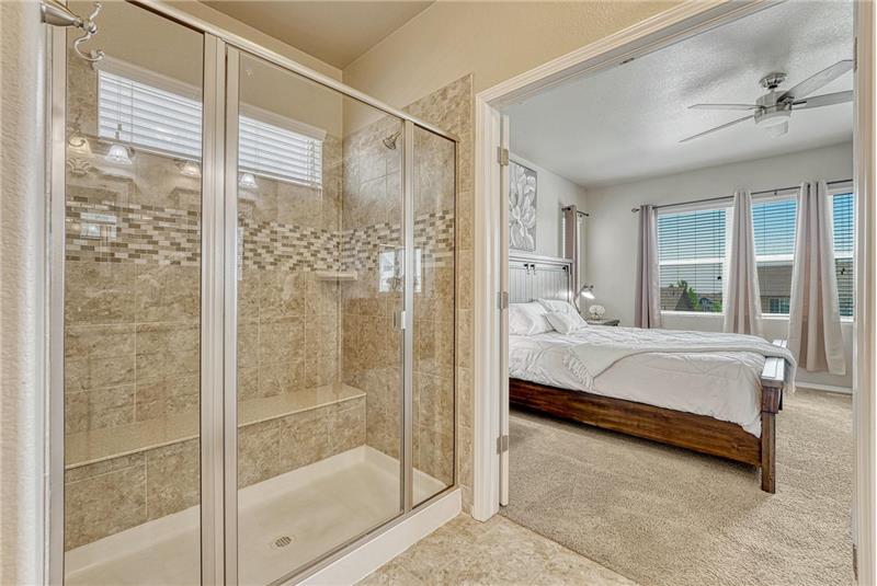Enclosed tiled shower with built-in seat in the Primary Bathroom.