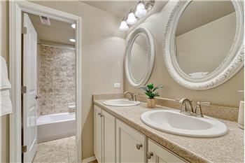 Basement Full Bathroom with dual sink vanity, framed mirrors, and tiled tub/shower.