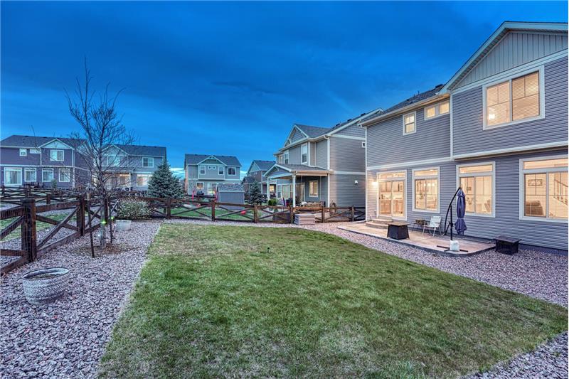 The fenced Backyard has a generous stretch of green grass surrounded by xeriscaped planting beds.