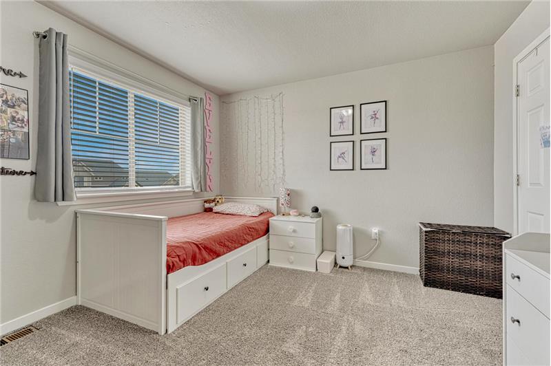 Upper Level Bedroom #1 with neutral carpet and a large view window with blinds and window treatments.