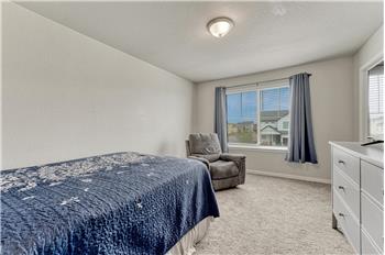 Upper Level Bedroom #2 with neutral carpet, and a large view window with blinds and window treatments.