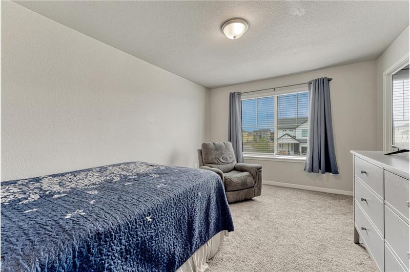 Upper Level Bedroom #2 with neutral carpet, and a large view window with blinds and window treatments.