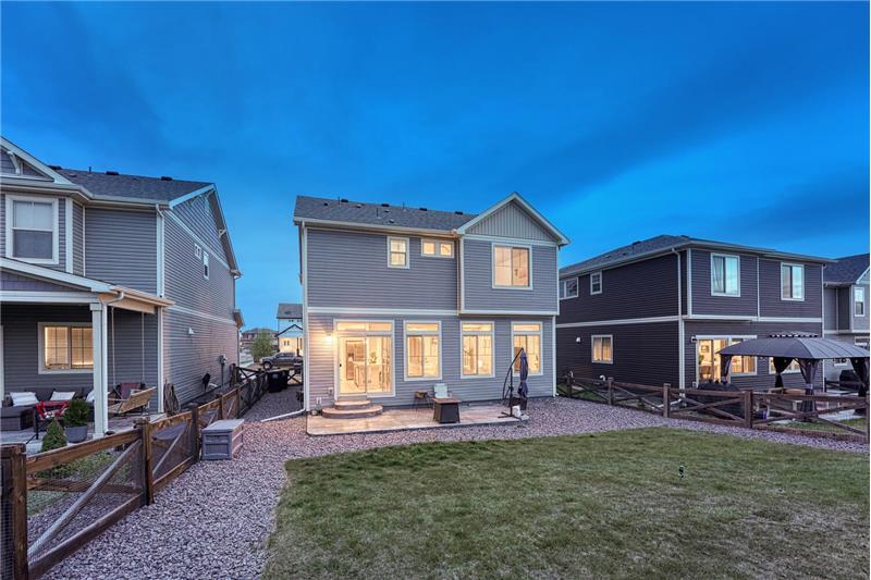 Sunset rear view of home, backyard, and patio.