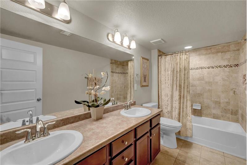 The Basement Bathroom features tile floors, a double sink vanity, and tiled tub/shower